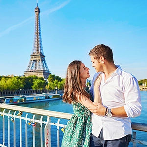Romantic couple enjoying a leisurely walk along the Seine River, with the Eiffel Tower in the background